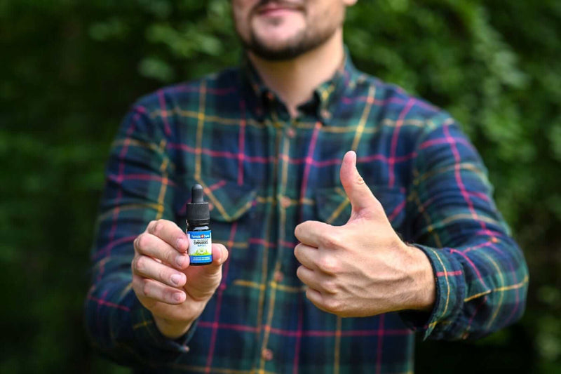 A man holding a 10 ml bottle of Formula Swiss CBD oil in hemp seed oil