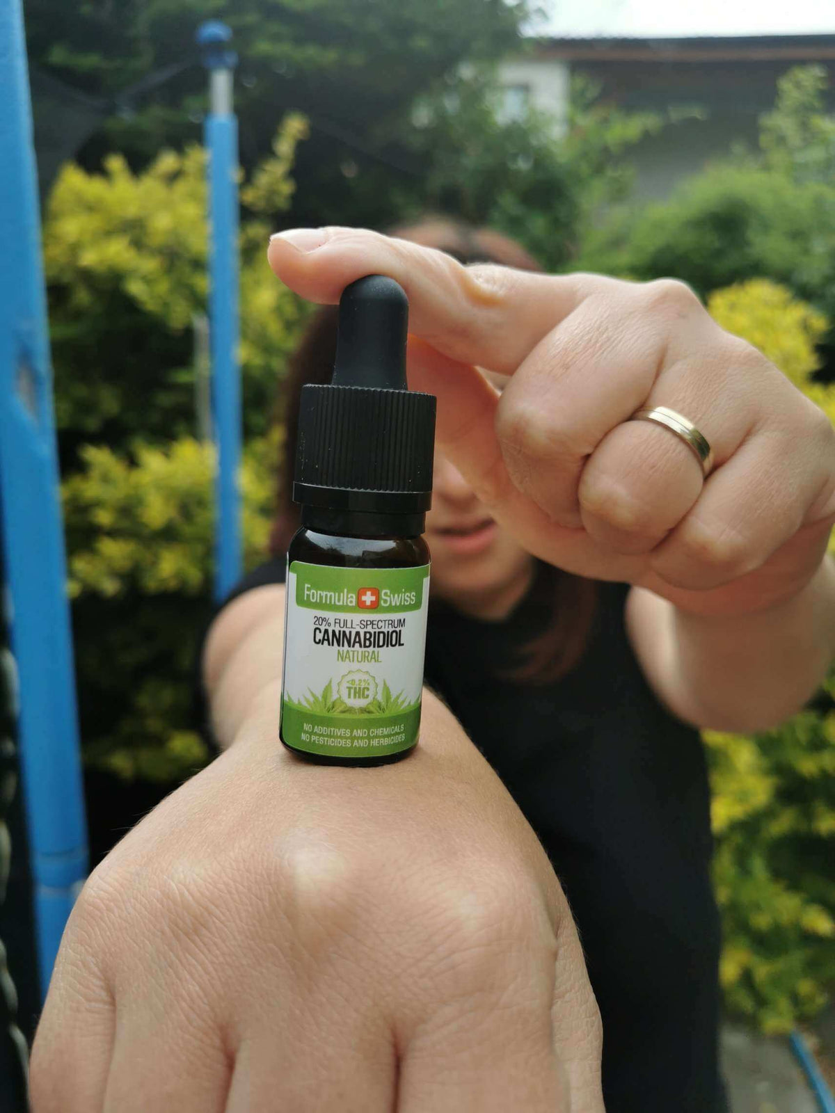 Pessoa com um frasco: óleo de CBD em óleo MCT natural (Formula Swiss)