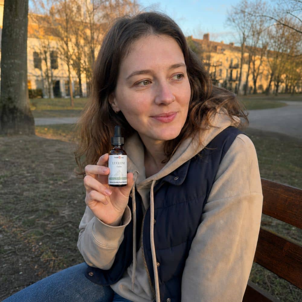 Mulher a segurar um frasco de óleo de CBD Lucerne ao ar livre, num parque
